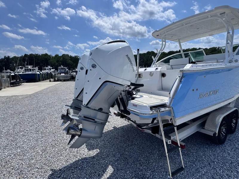 Slide: The Image of 2026 Blackfin 272 DC boat with Mercury outboard engine on a trailer, parked on gravel. - 4