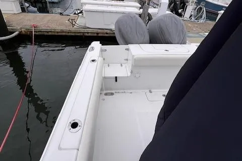 Slide: The Image of 2015 Sea Hunt Gamefish 25 boat docked, featuring a clean white deck and covered seats. - 7