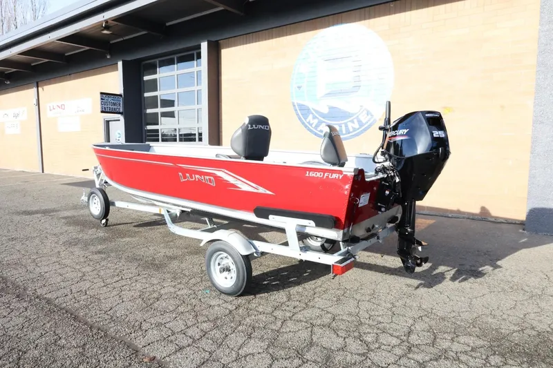 Slide: The Image of 2026 Lund 1600 Fury Tiller boat on trailer, red exterior, parked outside a building. - 10
