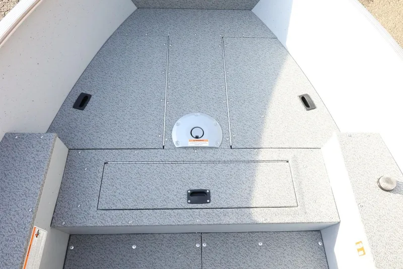 Slide: The Image of 2026 Lund 1600 Fury Tiller boat interior with storage compartments and textured flooring. - 13