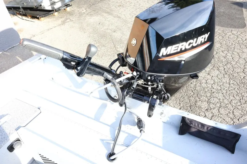 Slide: The Image of 2026 Lund 1600 Fury Tiller boat with Mercury outboard motor, parked on pavement. - 22