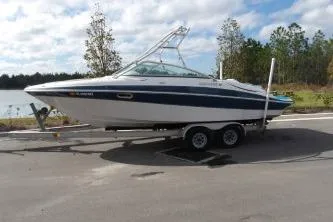 Slide: The Image of 2005 Four Winns 190 Horizon boat on trailer by a lake, under a cloudy sky. - 1
