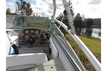 Slide: The Image of 2005 Four Winns 190 Horizon boat interior with steering wheel and dashboard by a lake. - 3