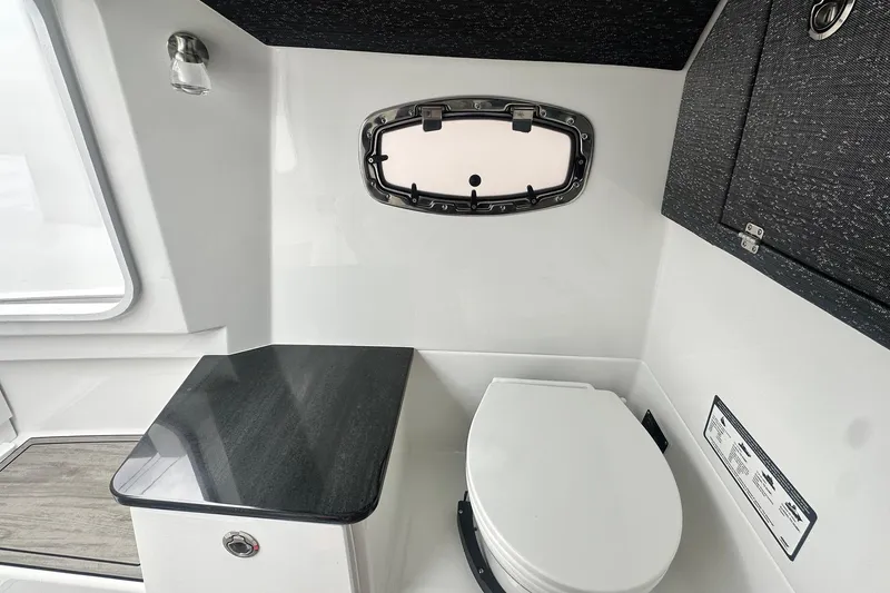 Slide: The Image of Interior of 2026 Monterey Elite 25 OB boat featuring a compact bathroom with a window. - 23