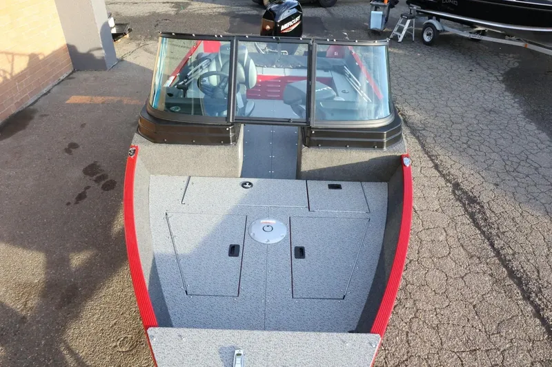 Slide: The Image of 2026 Lund 1650 Angler Sport boat with red accents, parked on pavement. - 9