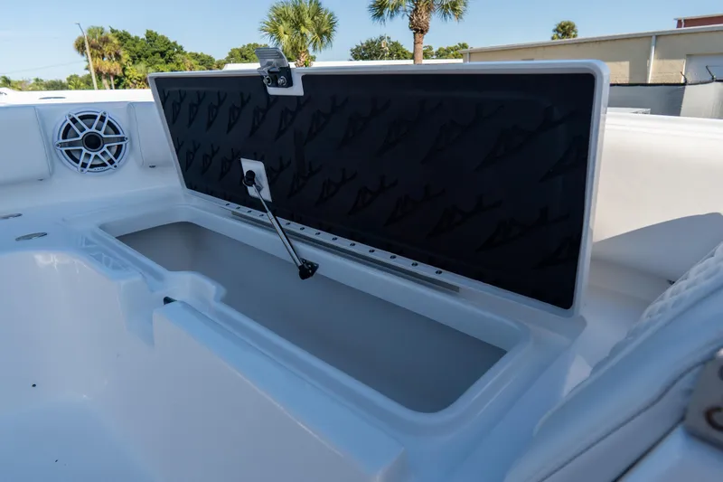 Slide: The Image of 2026 Tidewater 3100 Carolina Bay boat storage compartment with speaker, open lid, and scenic background. - 10