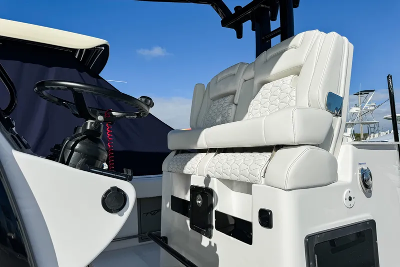 Slide: The Image of 2026 Tidewater 3100 Carolina Bay boat interior with white cushioned seating and steering wheel. - 22