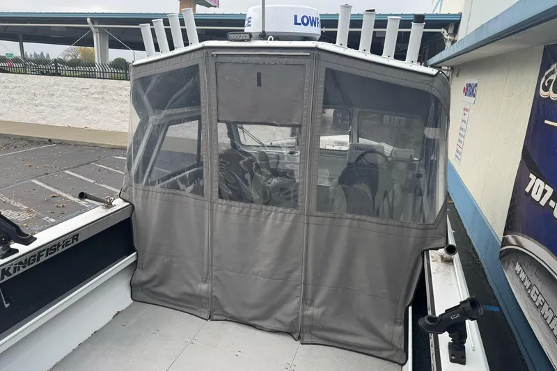 Slide: The Image of KingFisher 2025 Escape HHT boat with enclosed cabin, parked outdoors, 2021 model. - 10