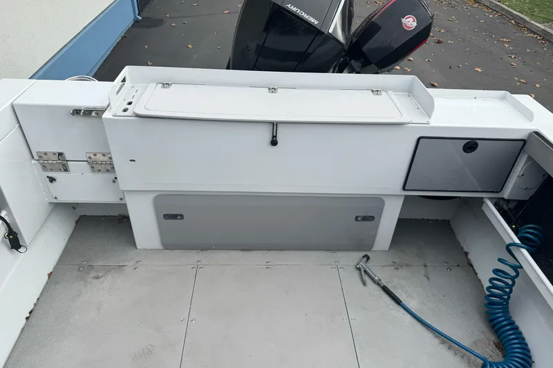 Slide: The Image of 2021 KingFisher 2025 Escape HHT boat interior with storage and Mercury outboard motor. - 13