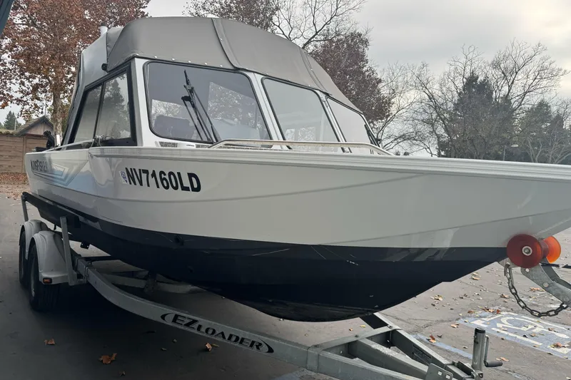 Slide: The Image of KingFisher 2025 Escape HHT boat on trailer, parked outdoors, autumn setting. - 3