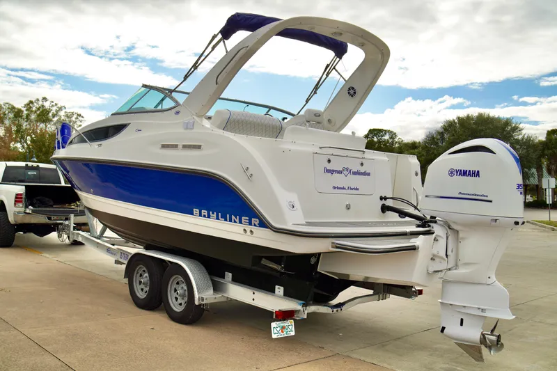 Slide: The Image of 2006 Bayliner 285 boat on trailer with Yamaha outboard motor, parked outdoors. - 1