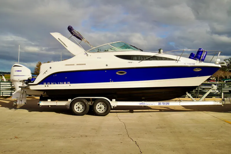 Slide: The Image of 2006 Bayliner 285 boat on trailer with Yamaha outboard motor, parked outdoors. - 2