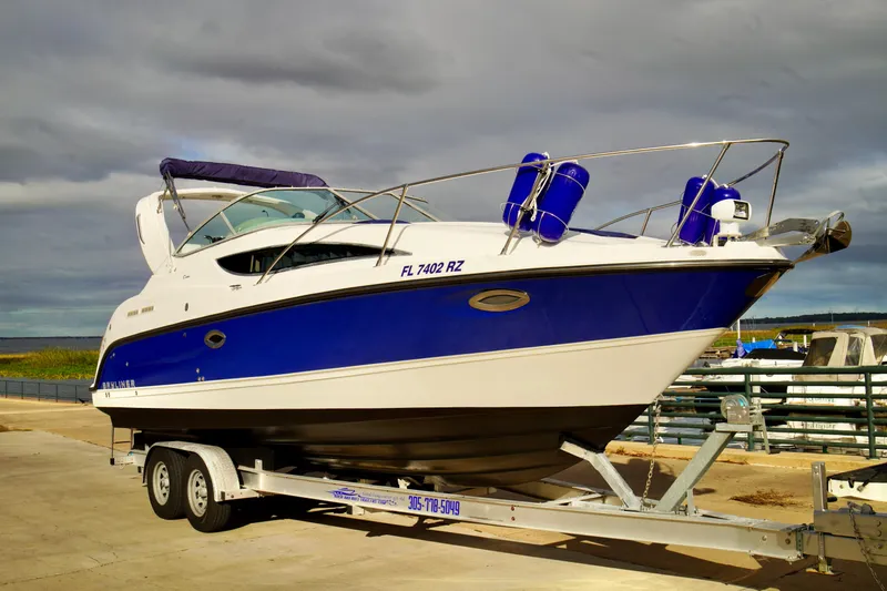 Slide: The Image of 2006 Bayliner 285 boat on trailer, blue and white design, dockside setting. - 4