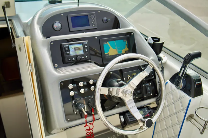 Slide: The Image of Control panel of a 2006 Bayliner 285 boat with steering wheel and navigation equipment. - 9
