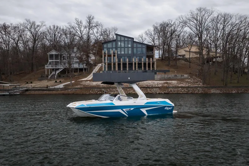 The Image of 2026 Tigé 22RZX boat on a lake, modern lakeside homes in the background. - 1