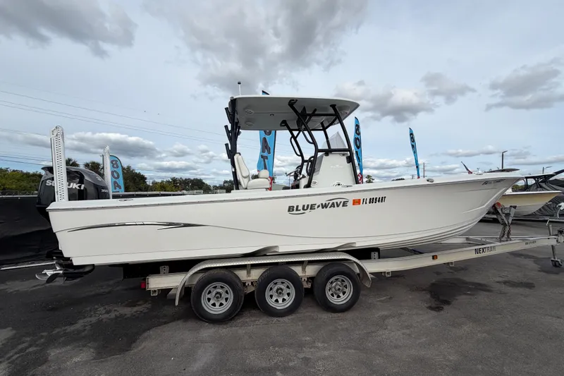 Slide: The Image of 2018 Blue Wave 2800 Pure Hybrid boat on trailer under clear blue sky. - 1