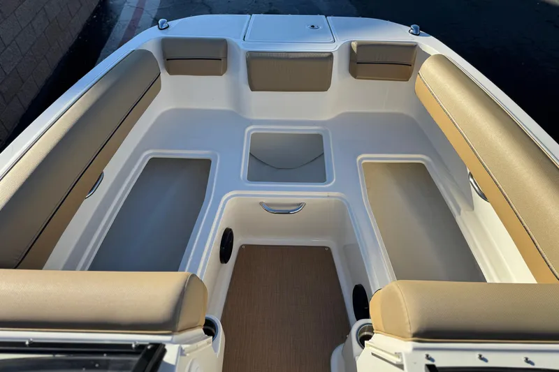 Slide: The Image of 2023 Bayliner DX 2050 boat interior with beige seating and storage compartments. - 15