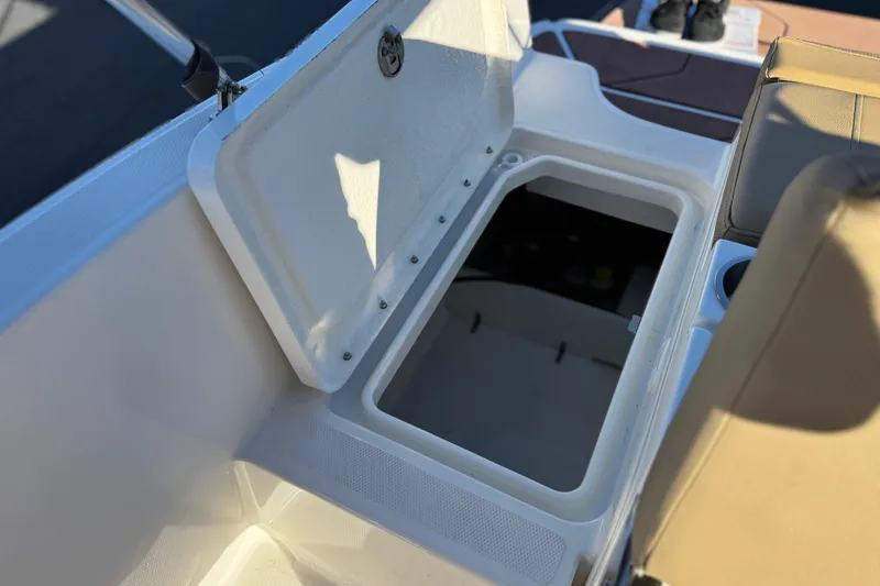 Slide: The Image of 2023 Bayliner DX 2050 boat storage compartment with open lid and seating area. - 19