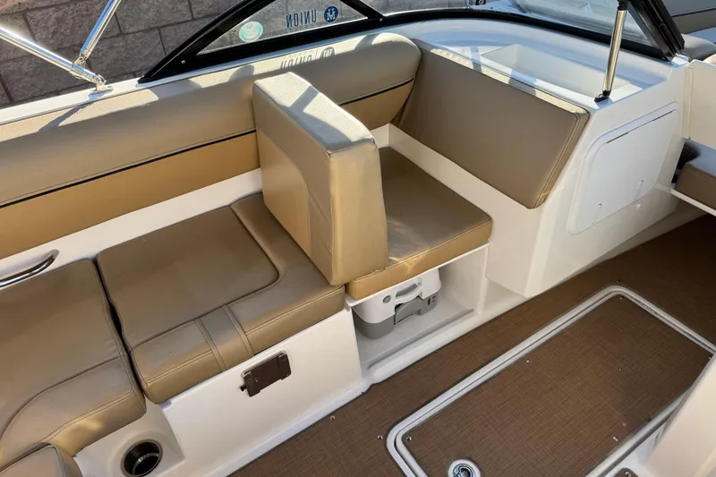 Slide: The Image of 2023 Bayliner DX 2050 interior seating with tan upholstery and storage compartment. - 22