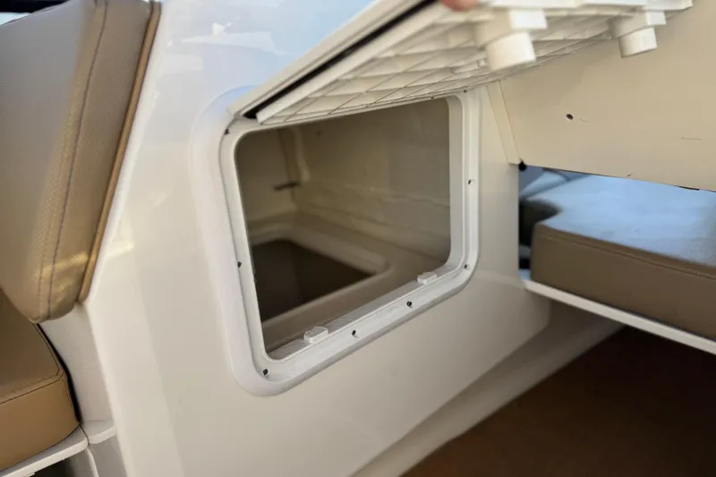 Slide: The Image of 2023 Bayliner DX 2050 boat storage compartment with open hatch and beige seating. - 25