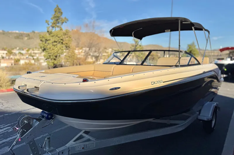 Slide: The Image of 2023 Bayliner DX 2050 boat on trailer, featuring sleek design and beige interior. - 3