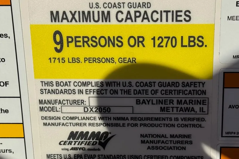 Slide: The Image of Bayliner DX 2050 boat capacity label, 9 persons or 1270 lbs, U.S. Coast Guard certified. - 32