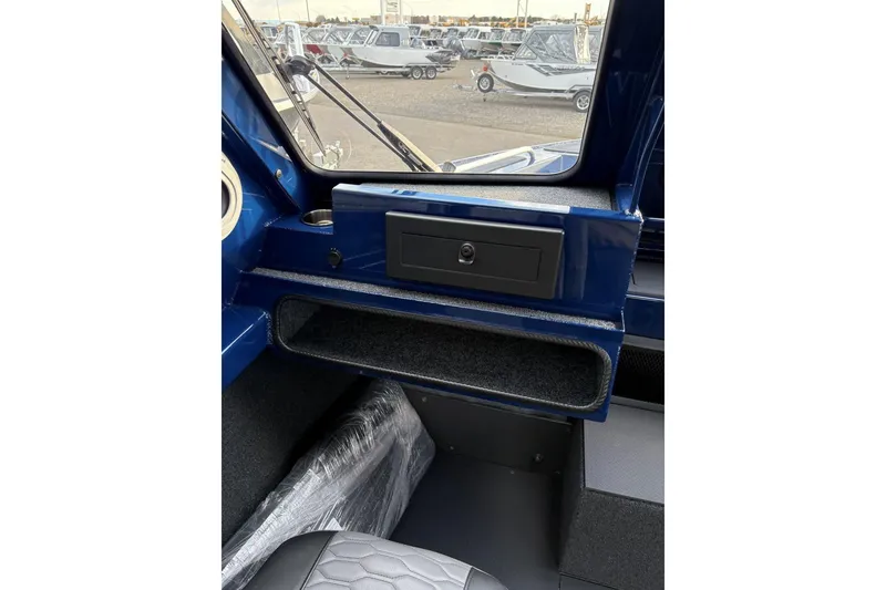 Slide: The Image of Interior view of 2026 Weldcraft 210 Revolution HT boat, featuring dashboard and storage compartment. - 19