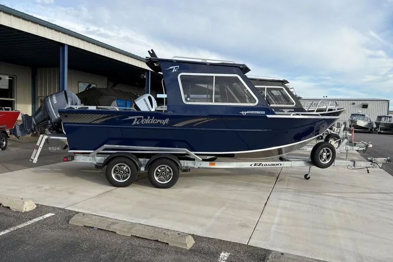 The Image of 2026 Weldcraft 210 Revolution HT boat on trailer, parked outside a building. - 12