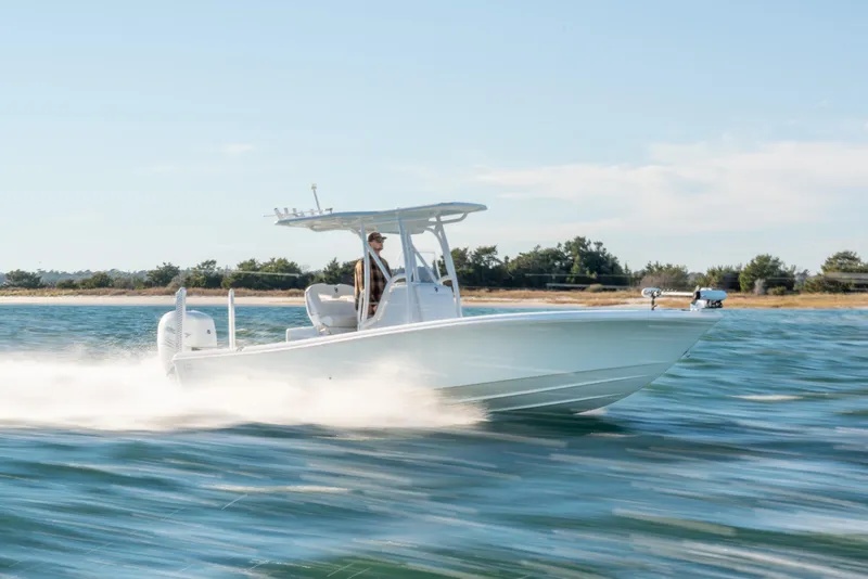 Slide: The Image of 2020 BARKER 26 boat speeding on water near a shoreline under a clear sky. - 3