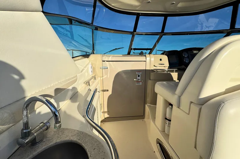 Slide: The Image of 2008 Sea Ray 38 Sundancer cockpit with helm, sink, and seating under blue sky. - 23