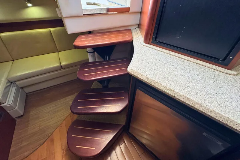 Slide: The Image of Interior of 2008 Sea Ray 38 Sundancer with wooden steps and beige seating. - 26