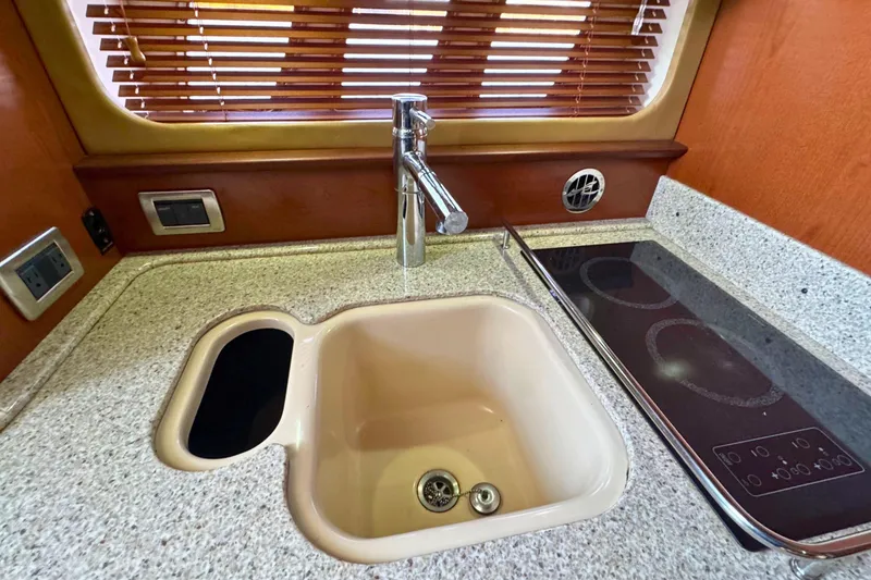 Slide: The Image of 2008 Sea Ray 38 Sundancer kitchen with sink, stovetop, and wooden blinds. - 30