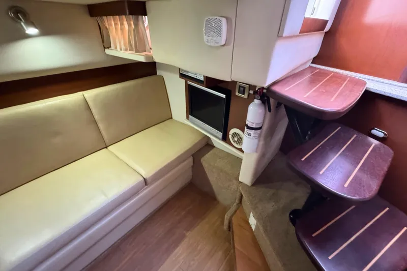 Slide: The Image of Interior of 2008 Sea Ray 38 Sundancer with beige seating, TV, and wooden steps. - 33