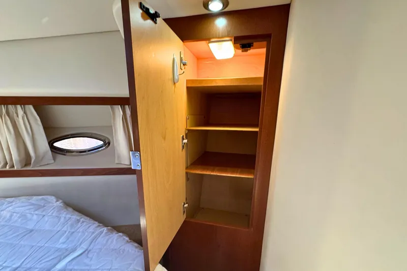 Slide: The Image of Interior of 2008 Sea Ray 38 Sundancer showing open wooden cabinet and bed. - 44