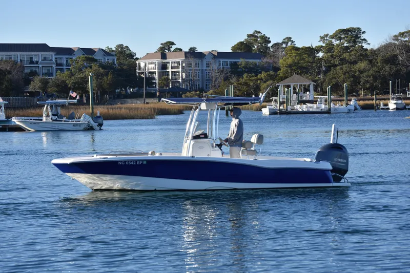Slide: The Image of 2017 NauticStar 231 Angler boat cruising on a calm waterway near docks and buildings. - 4