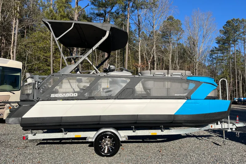 Slide: The Image of 2023 Sea-Doo Switch Cruise 21 pontoon boat on trailer in wooded area. - 23