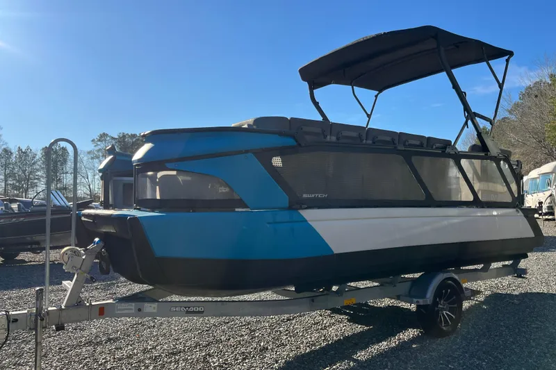 Slide: The Image of 2023 Sea-Doo Switch Cruise 21 pontoon boat on trailer, blue and white design. - 4
