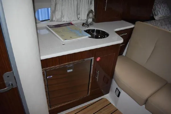 Slide: The Image of 2015 Regal 32 Express boat interior with kitchenette, sink, and seating area. - 14