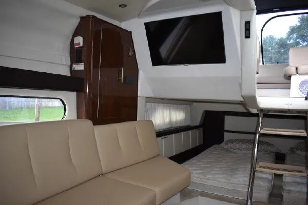 Slide: The Image of 2015 Regal 32 Express interior with beige seating, bed, TV, and wooden cabinetry. - 15