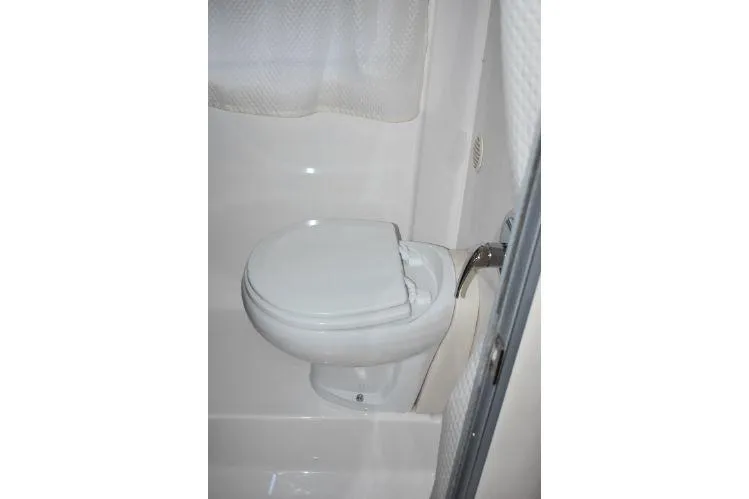 Slide: The Image of 2015 Regal 32 Express boat bathroom with white toilet and shower curtain. - 19
