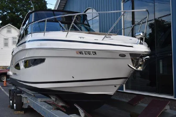 Slide: The Image of 2015 Regal 32 Express boat on trailer, parked near a building. - 2