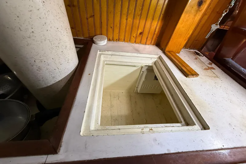 Slide: The Image of Interior view of a 1992 Treworgy 65 Schooner, featuring a wooden hatch and storage area. - 17