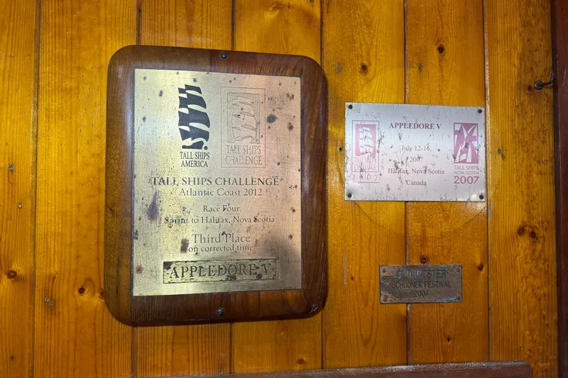 Slide: The Image of Plaques on wooden wall commemorating Tall Ships Challenge achievements, featuring Appledore V. - 18