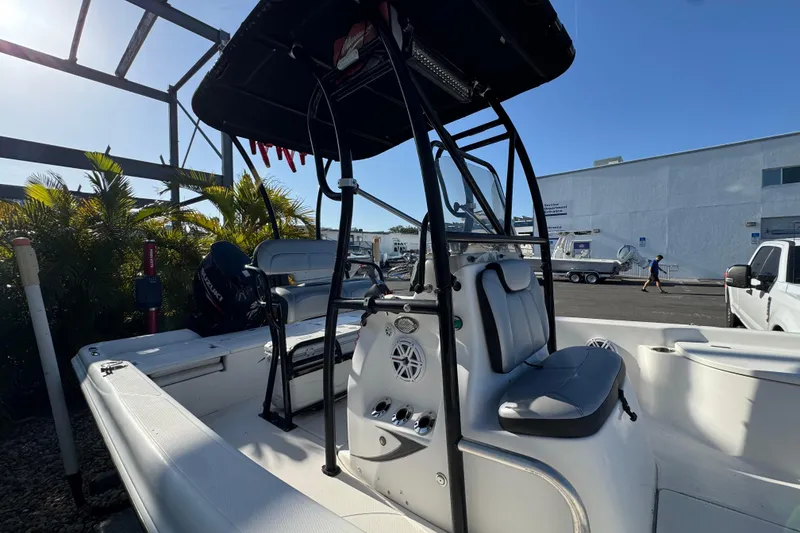 Slide: The Image of 2016 Blue Wave 2200 boat with T-top and seating, parked outdoors. - 10