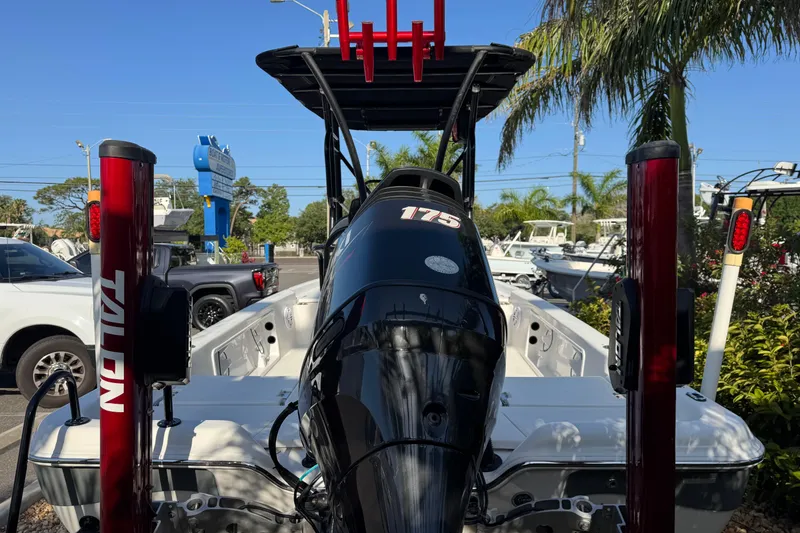 Slide: The Image of 2016 Blue Wave 2200 boat with 175 HP engine, parked outdoors near palm trees. - 20