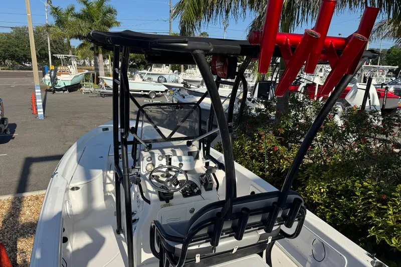 Slide: The Image of 2016 Blue Wave 2200 boat with T-top and fishing rod holders in a marina setting. - 27