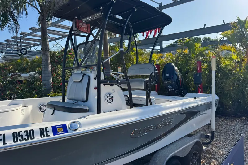 Slide: The Image of 2016 Blue Wave 2200 boat with T-top and outboard motor, parked on a trailer. - 4