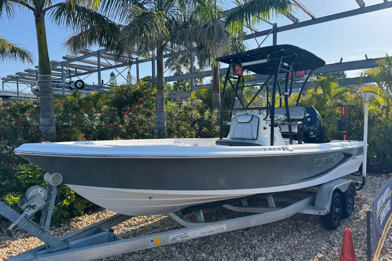Slide: The Image of 2016 Blue Wave 2200 boat on trailer, surrounded by palm trees and greenery. - 5