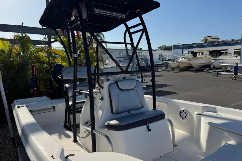 Slide: The Image of 2016 Blue Wave 2200 boat with T-top, docked in a marina under clear skies. - 9