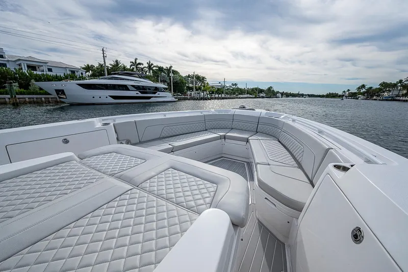 Slide: The Image of 2023 Intrepid 427 Nomad SE boat interior with luxurious seating on a calm waterway. - 1